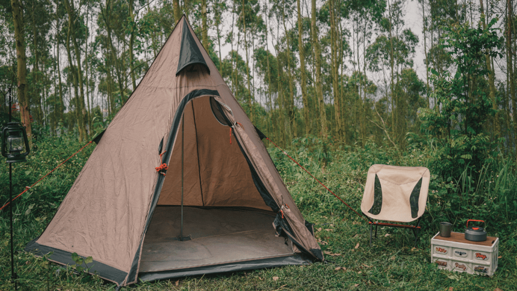 a tent in the middle of a field with a chair next to it