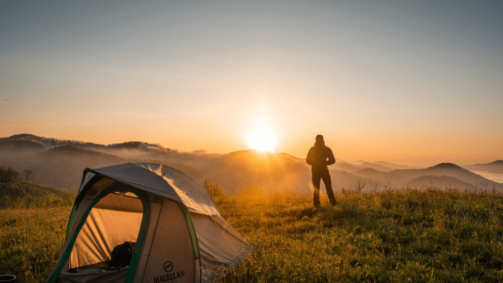 a person standing in front of a tent at sunset