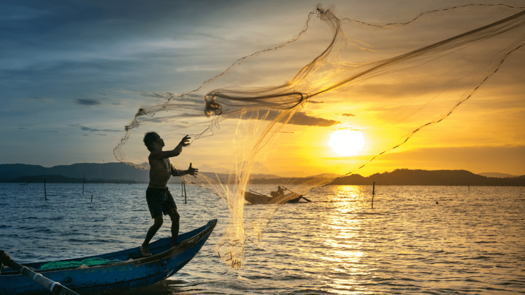 a person in a boat throwing a net into the water at sunset