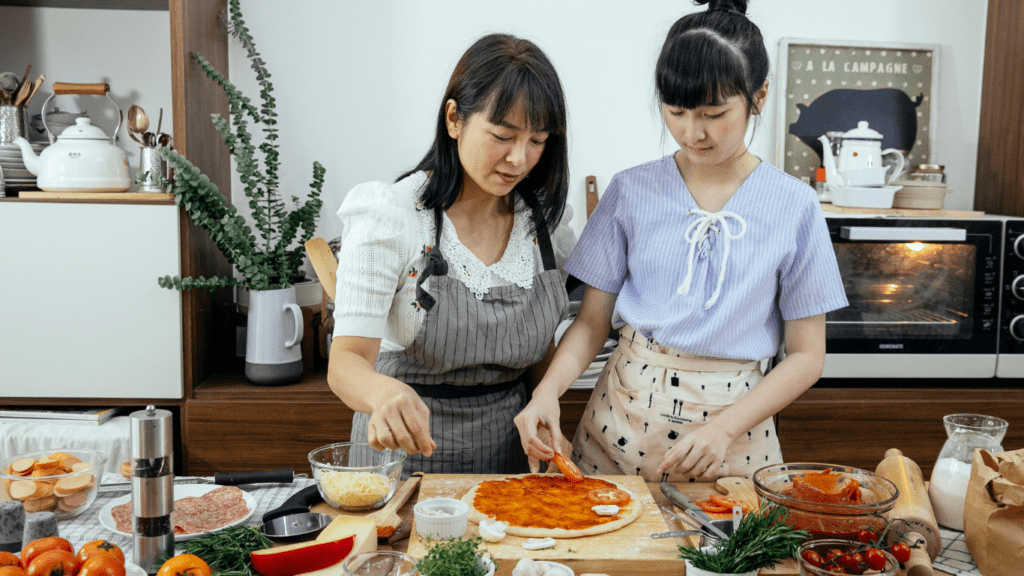 two people preparing food in the kitchen