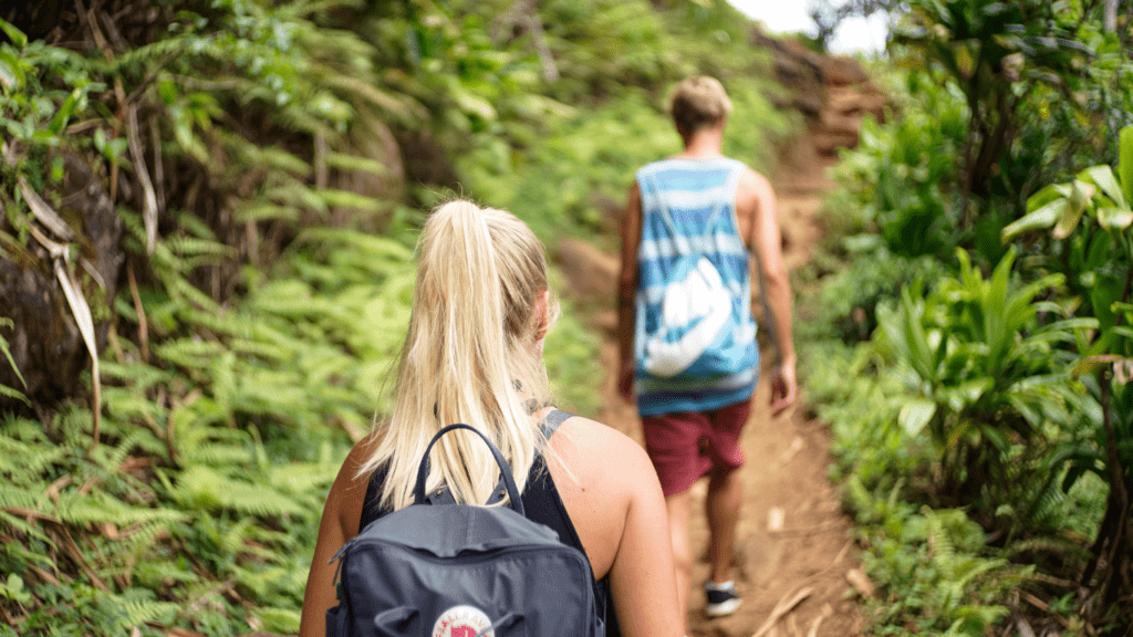 two people with backpacks walking down a trail