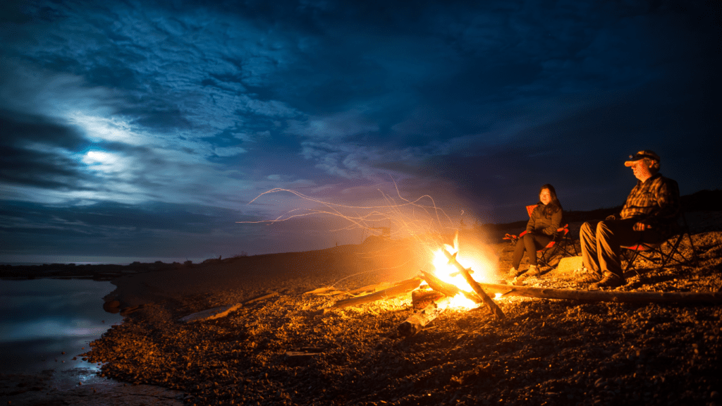 a group of people sitting around a campfire at night