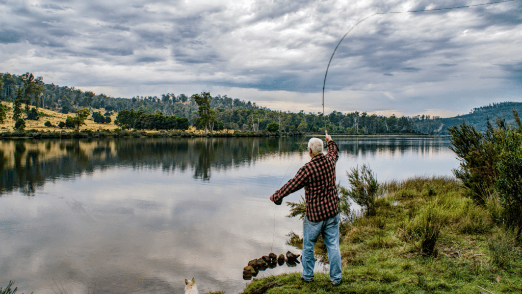 a person is holding a fishing rod while standing next to a body of water