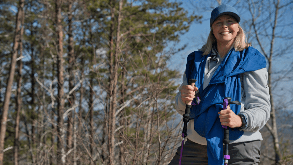 a person wearing a winter jacket and hiking poles in the woods