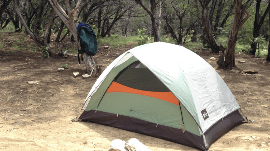 a tent in the middle of a field with a chair next to it