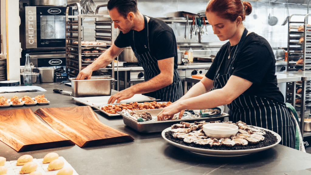 two people preparing food in the kitchen