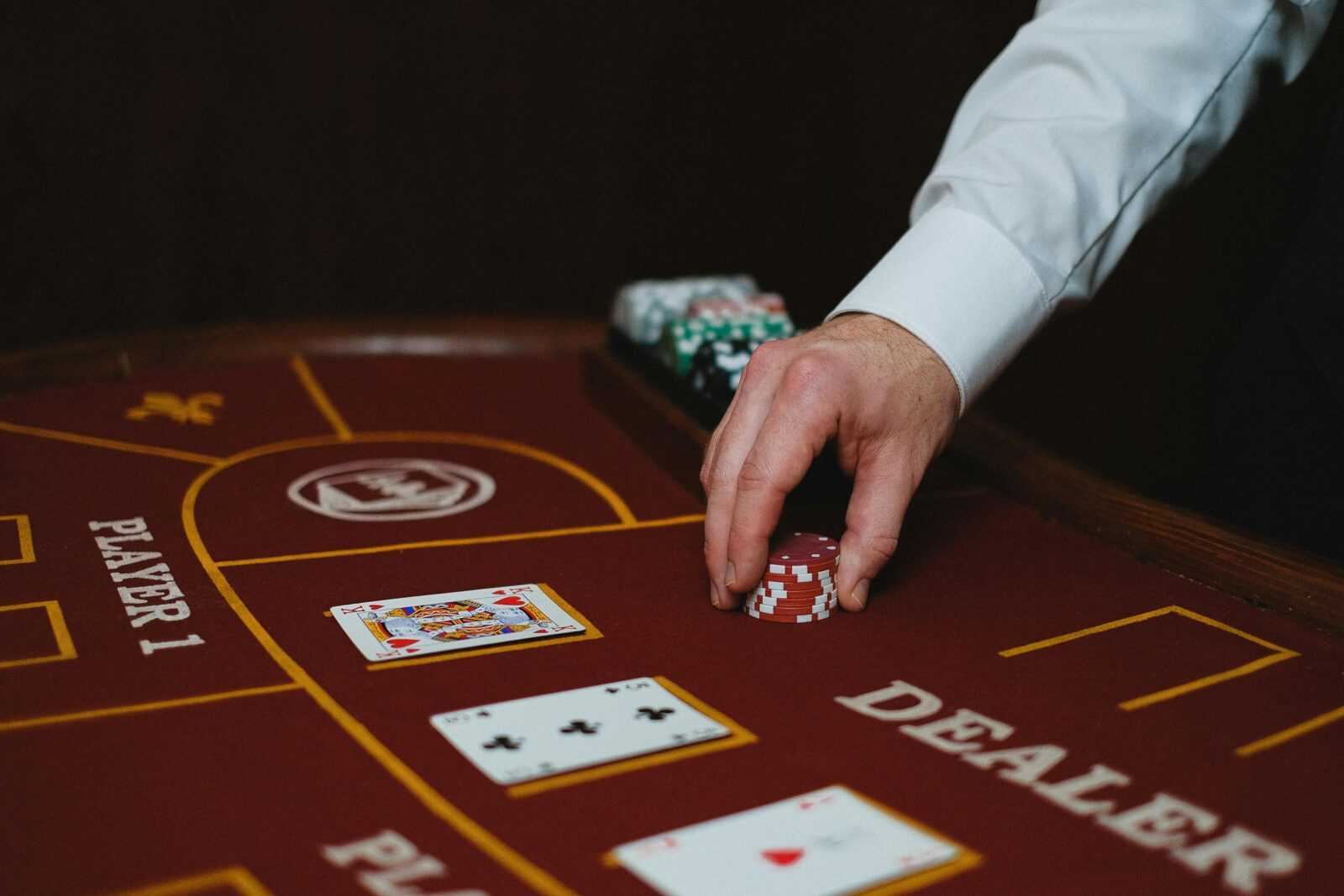 Close-up of a dealer handling poker chips on a casino table, showcasing cards and layout.